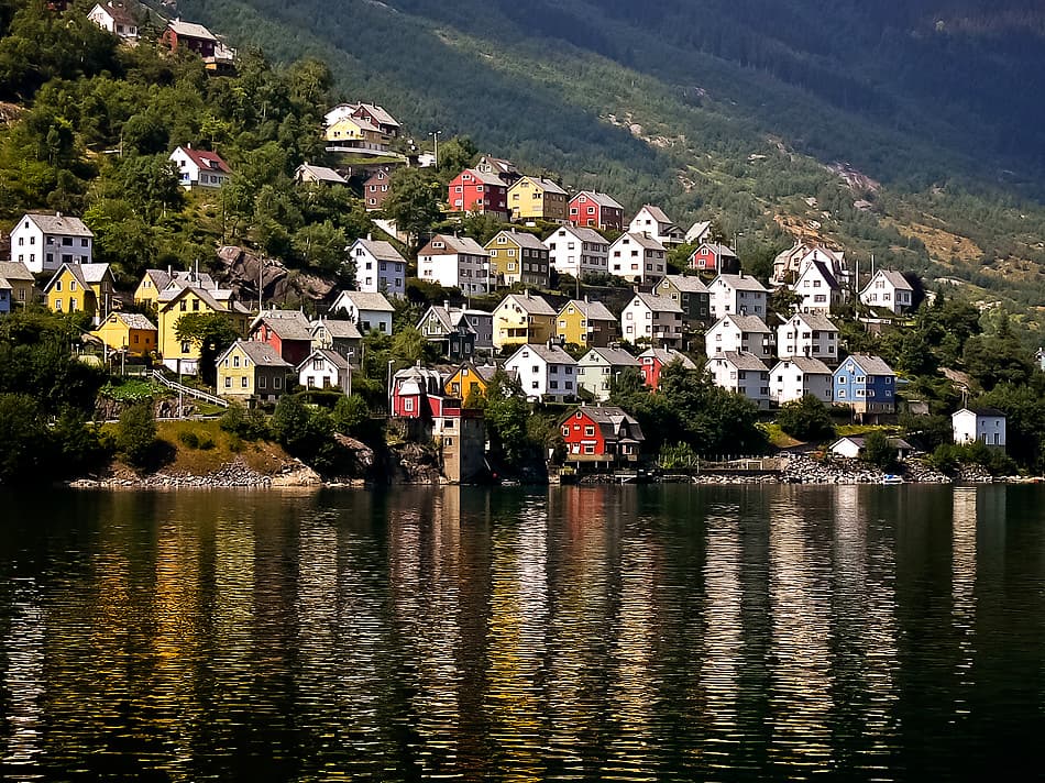 Inner Hardangerfjord with steep green valley walls, calm water reflecting surrounding mountains near Odda