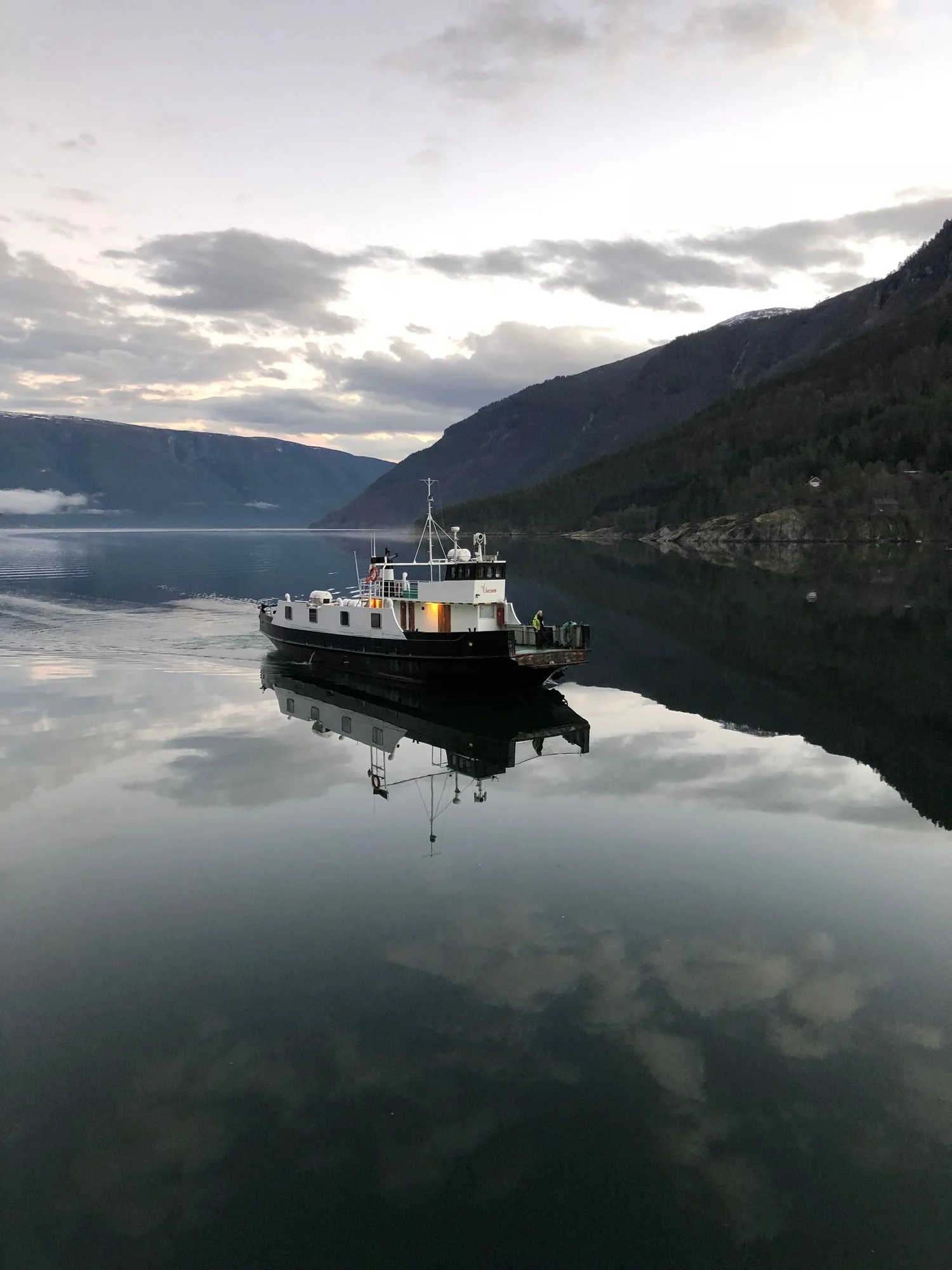 The Urnes ferry crossing a calm Lustrafjord at first light