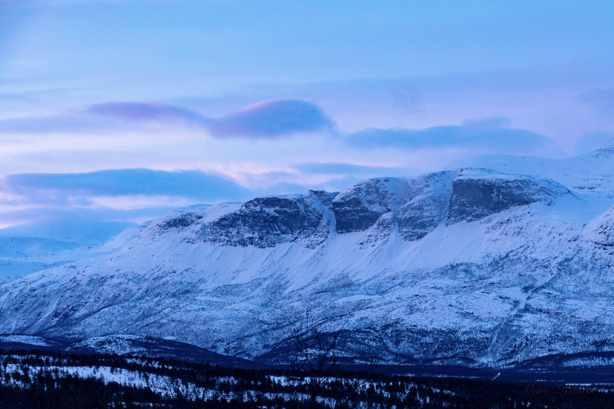 Snow-covered mountains above Skibotn under pale blue and pink midwinter light